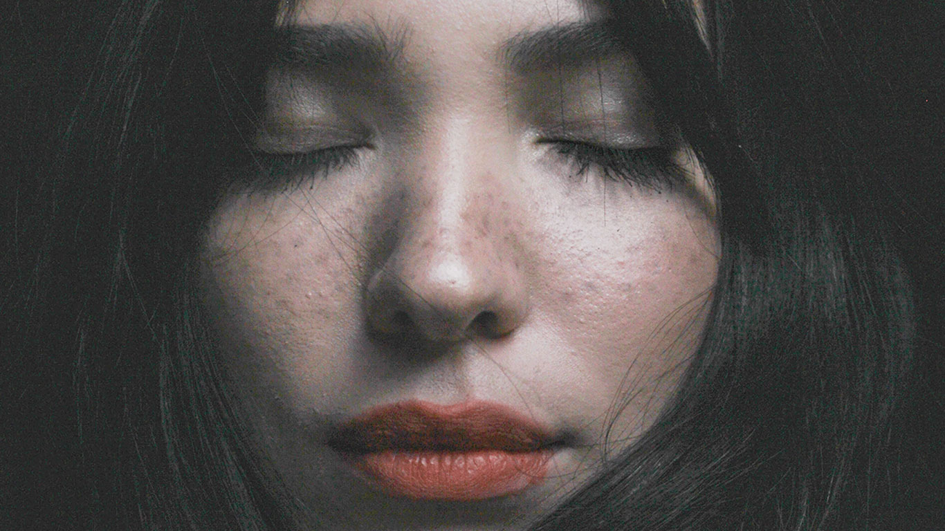 Nahaufnahme des Gesichts einer Frau mit geschlossenen Augen beim Meditieren