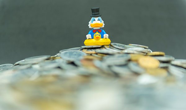 Dagobert Duck sitzt auf einem Geldberg