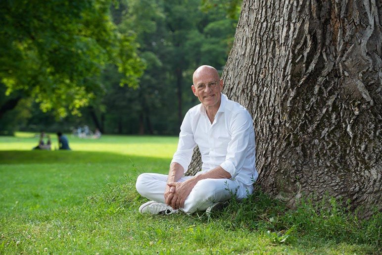 Dr. Ulrich Bauhofer sitzt auf einer Wiese vor einem Baum.