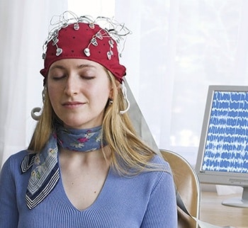 Eine Frau ist an einem EEG angeschlossen, zur Messung der Gehirnwellen während der Meditation.