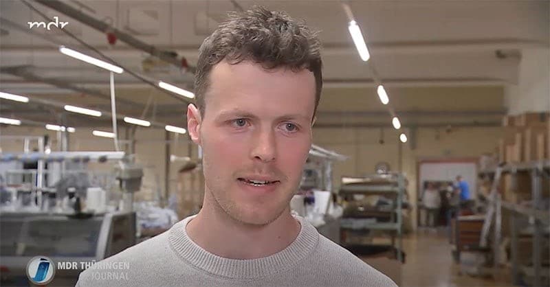 Charlie Stein trägt seinen Pullover und steht in der Textilproduktion