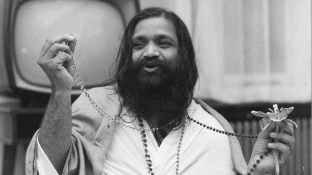 Schwarz-Weiß-Aufnahme von Maharishi Mahesh Yogi, welcher eine Blume hält.