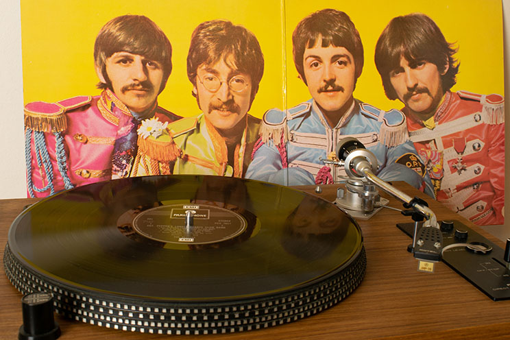 Bild der vier Beatles hinter einem Plattenspieler.
