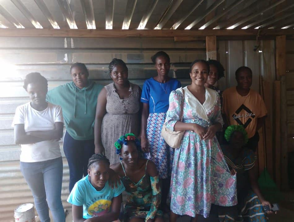 Mehrere afrikanische Personen in einer Wellblech-Hütte in Windhoek